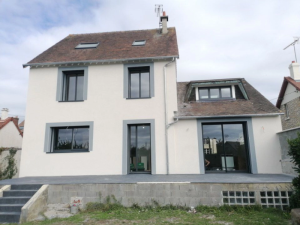 Maison crepi beige, menuiseries anthracite et terrasse carrelee grise sur elevee