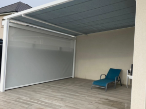 Pergola blanche toile grise, store latéral beige sur carrelage effet bois