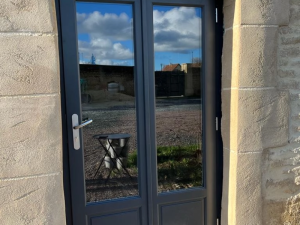 Porte-fenêtre double anthracite, grandes vitres et soubassement plein sur pierre