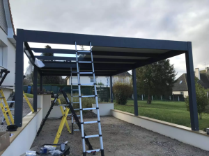 Montage pergola aluminium anthracite toit plat contre facade blanche