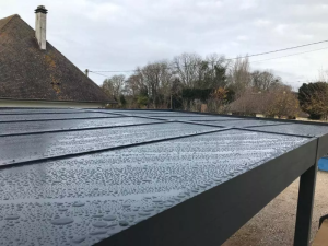 Toiture carport anthracite humide, gouttes d'eau sous ciel gris