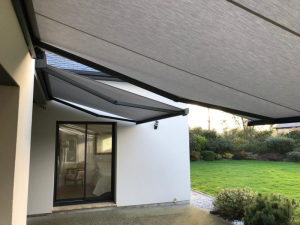 Deux stores bannes gris clair déployés, table et chaises sur terrasse béton