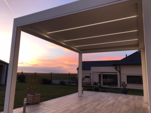 Pergola blanche LED sous lames, terrasse effet bois au coucher du soleil