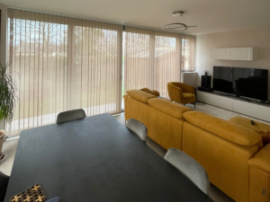 Salon moutarde, store californien beige sur grande baie coulissante jardin