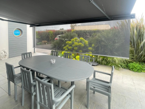 Store banne gris et screen vertical au-dessus d'une table ovale sur terrasse carrelee