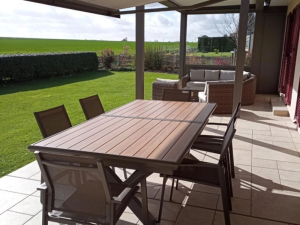 Pergola toiture beige, poteaux anthracite, salon exterieur face aux champs