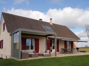 Pergola bioclimatique grise et store banne anthracite devant volets bordeaux