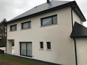 Maison neuve crepi clair, baies coulissantes et fenetres noires sous toit ardoise