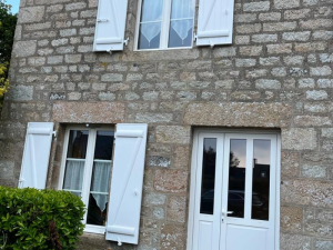 Fenetre blanche volets Z ouverts et porte vitree sur mur pierre