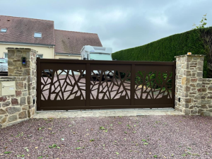 Portail coulissant brun motifs cristaux ajourés entre piliers pierre naturelle