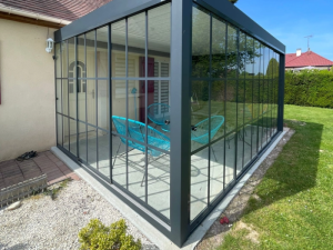 Verrière anthracite style atelier, chaises turquoise Acapulco sur dalle et pelouse