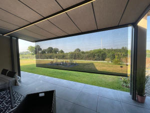 Pergola toiture tissu, store vertical gris et LED sur terrasse carrelee