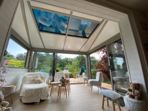 Interieur veranda lambris blanc, fauteuil moelleux et lanterne vitree sous puits de lumiere