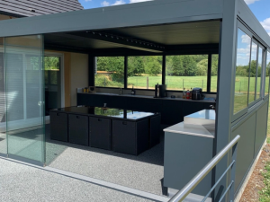 Pergola cuisine extérieure anthracite, plan bar noir et baie coulissante sur champ