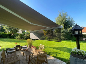 Store banne taupe, lambrequin gris, salon exterieur pierre et jardin vert