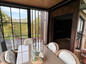Salle à manger rotin sous veranda, vitrage atelier et lames bois brise-vue