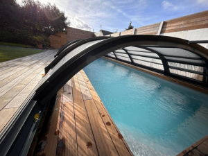 Abri piscine telescopique anthracite, eau turquoise et terrasse bois