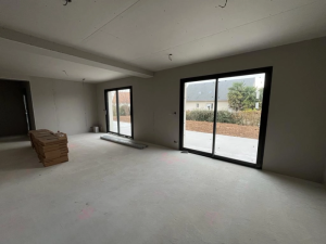 Chantier interieur, double baie coulissante noire sur dalle beton et jardin visible