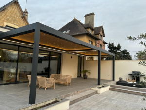 Pergola noire plafond bois, spots LED et salon rotin sur terrasse carrelée