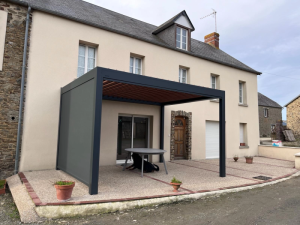 Pergola bioclimatique anthracite, lames effet bois et store lateral gris sur terrasse gravier
