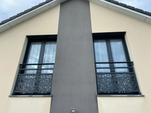 Deux fenetres avec garde-corps noir motif floral sur bandeau gris
