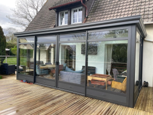 Veranda anthracite baies coulissantes sur terrasse bois, maison tuiles
