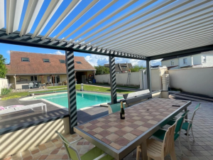 Pergola bioclimatique anthracite, lames blanches obliques et ombres sur table carrelée