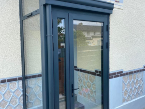 Sas entrée anthracite vitré, porte alu et frise bleue décorative sur crépi