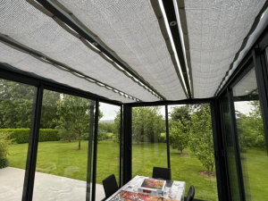 Interieur veranda, store plafond tissu gris et baies vitrees sur jardin