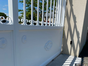 Gros plan portail blanc medallions volutes, ombre sur pilier pierre