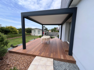 Pergola adossée blanche, lames blanches fermees sur deck bois et shed blanc au fond