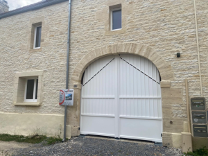 Portail blanc ajoure sous voute pierre devant facade moellons
