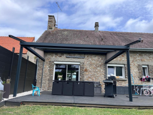 Pergola toile rétractable anthracite adossée pierre, store latéral sur terrasse bois