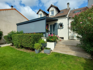 Pergola grise, screen zip lateral sur terrasse bois et marches vers pelouse fleurie
