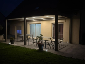 Pergola anthracite nocturne, LED plafond et spots au sol, table et bancs gris