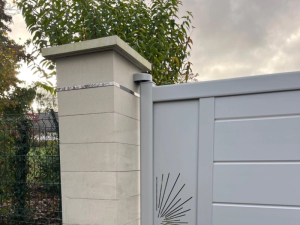 Detail portail gris clair decoupe soleil sur pilier pierre beige