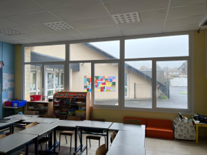 Baie vitrée blanche multi-vitrages dans salle de classe avec tables et étagères