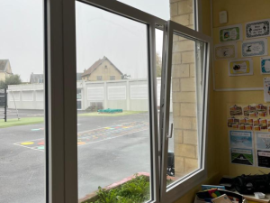 Fenêtre PVC blanche oscillo-battante entrouverte, cour de récréation vue depuis une classe