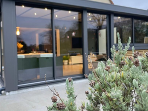 Véranda anthracite baies vitrées, spots extérieurs et intérieur éclairé au crépuscule