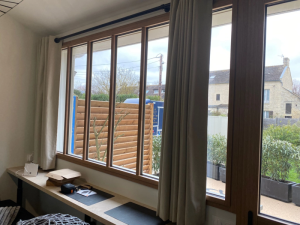 Interieur, longue fenetre effet bois au-dessus bureau, vue claustra et jardinières