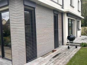 Bardage bois clair, BSO noirs et baie anthracite sur terrasse bois