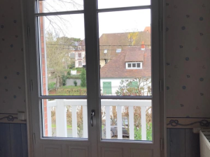 Porte-fenêtre blanche petits-bois, balcon barreaux, pièce aux murs bleu à motifs