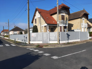 Cloture grise lames verticales angle maison pierre tuiles rouges