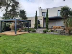 Deux pergolas anthracite, terrasse bois et pierre devant maison contemporaine