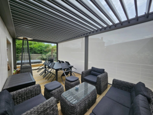 Pergola grise, lames orientables et stores latéraux crème sur terrasse en bois