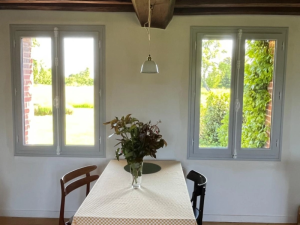 Deux fenetres gris clair cremones blanches, table jaune sous poutres bois