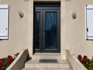 Porte anthracite vitrage géométrique, marches carrelées et rhododendrons rouges