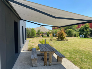 Store banne gris clair anthracite, table pique-nique bois facade moderne
