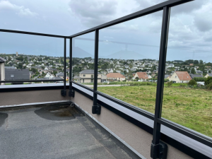 Garde-corps verre et alu noir sur terrasse EPDM grise, vue lotissements et campagne