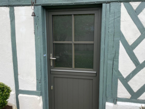 Porte semi-vitrée anthracite quadrillée dans encadrement colombages vert et crépi blanc